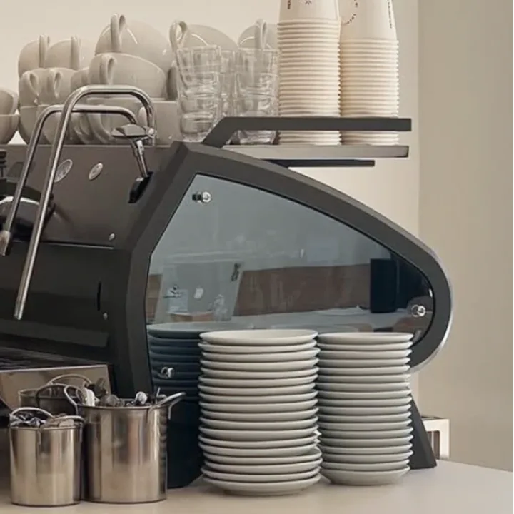 Maquina de espresso con tazas apiladas en la zona de servicio.